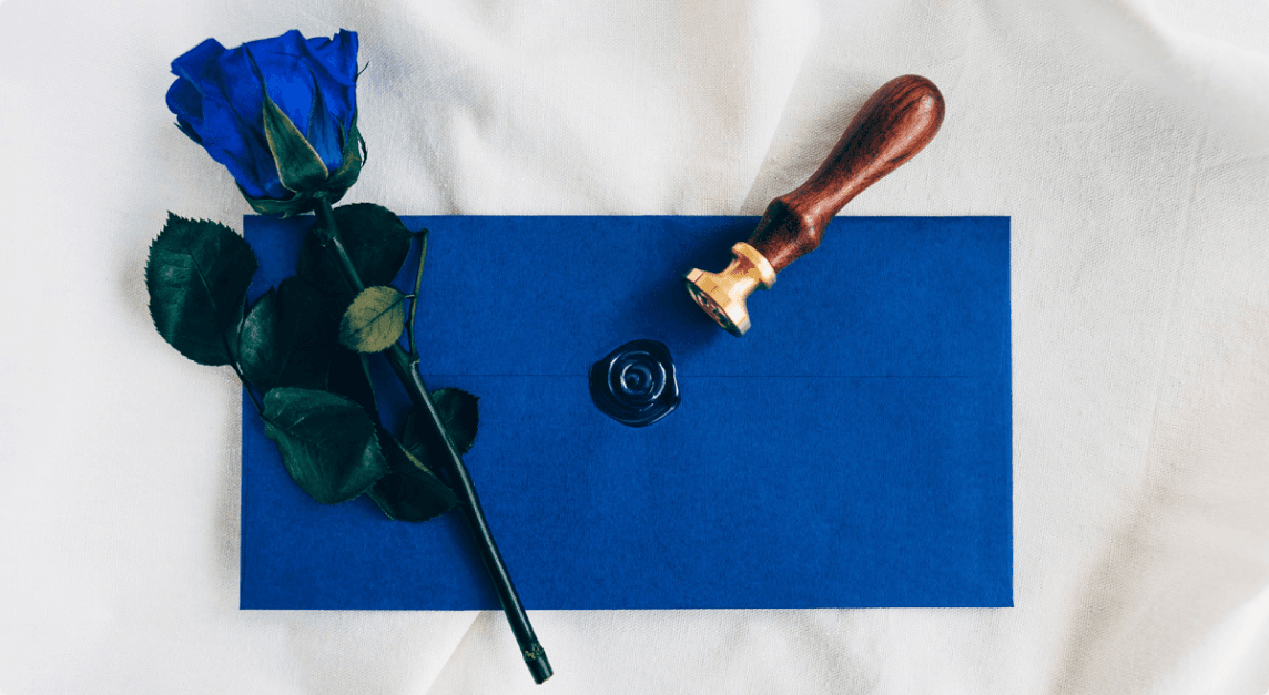 A blue rose beside a wax-sealed blue envelope